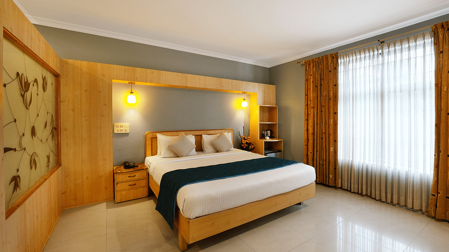 A spacious Suite with a king size bed and large windows - Cross Roads Inn, Bengaluru