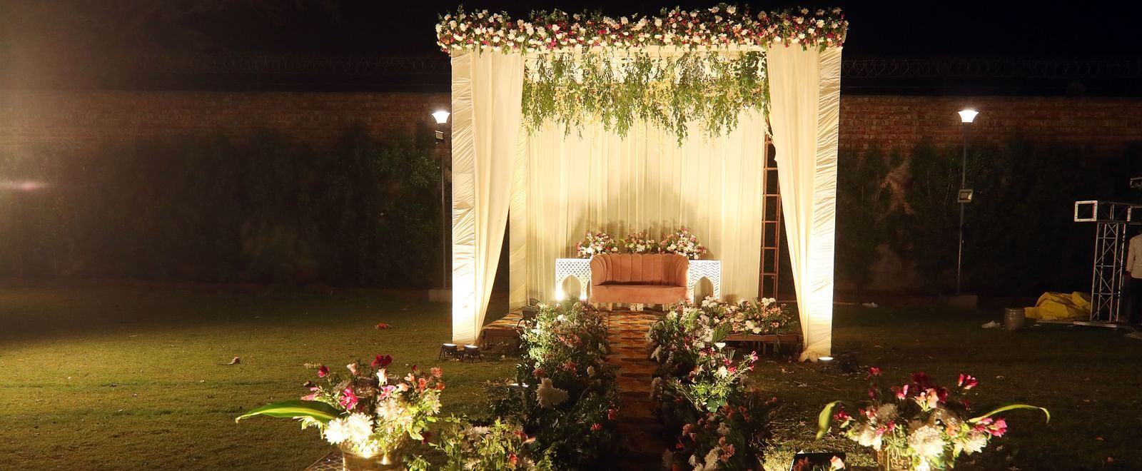 Wedding mandap with floral decor and seating arrangement on a lawn at Tisya Farms, Gurgaon.