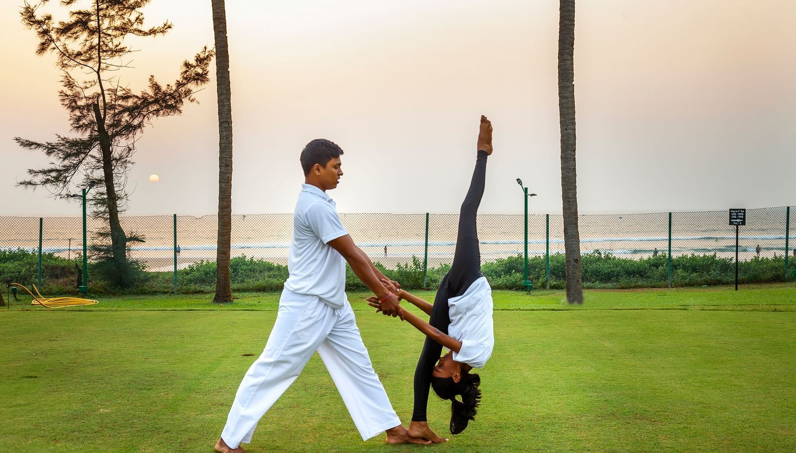 two people doing an asana on the lawn - Caravela Beach Resort Goa