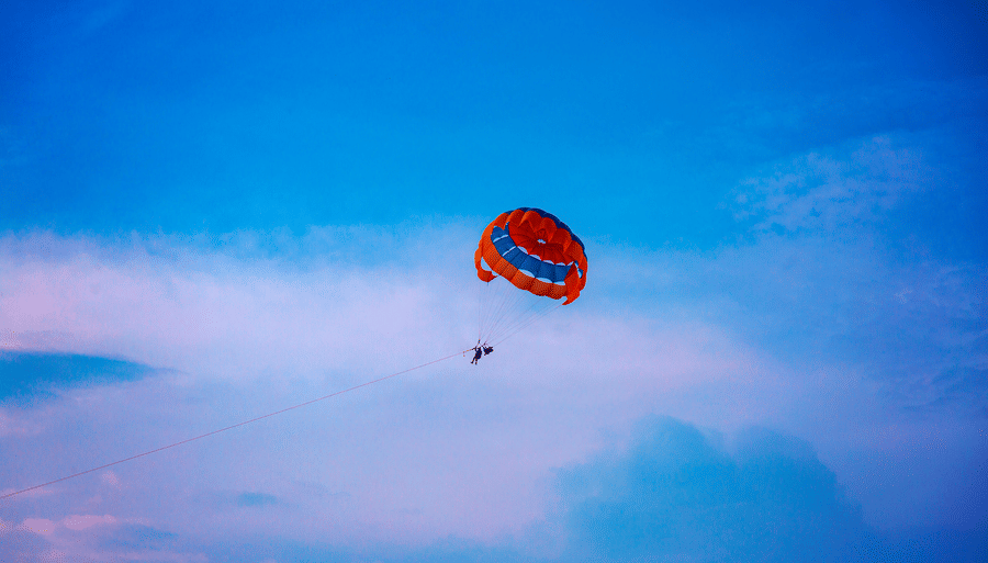 a person paragliding with a colourful parachute and blue sky in the background
