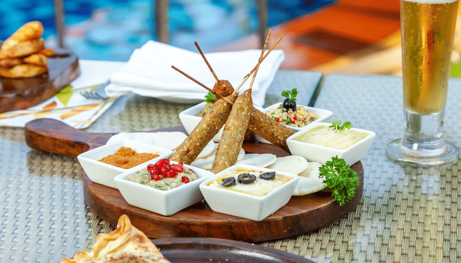many sheek kebabs kept on a table with dips next to it - Caravela Beach Resort Goa