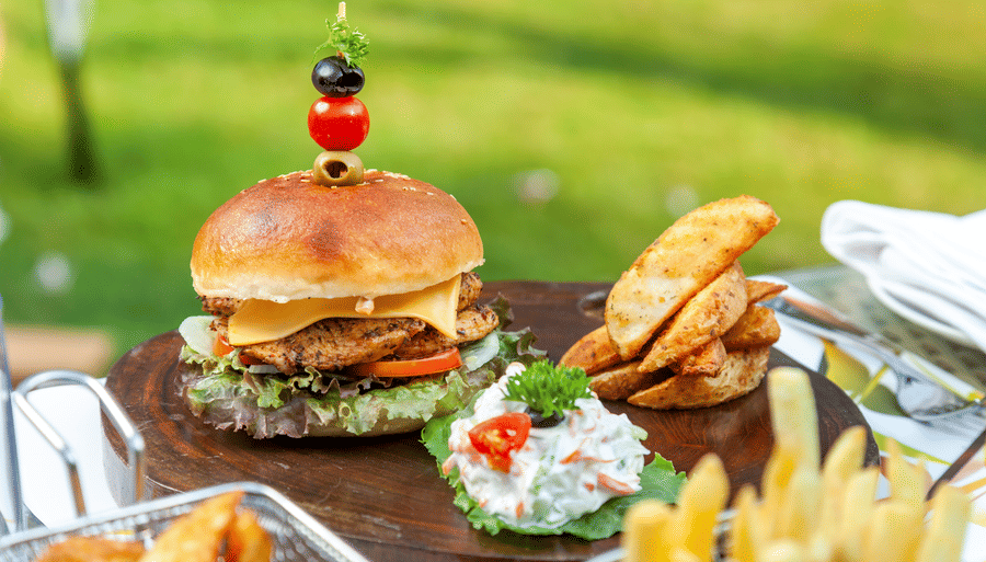 a burger with sides kept on a table - Caravela Beach Resort Goa