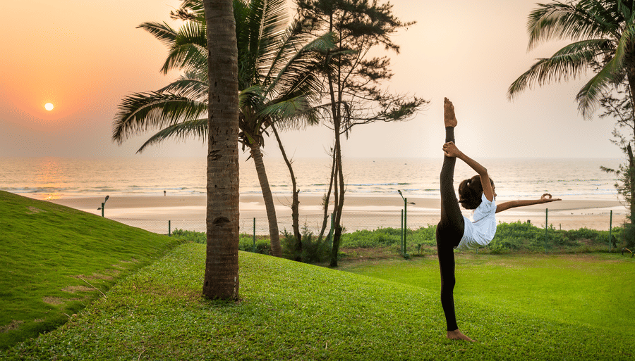 a person doing an asana on the lawn - Caravela Beach Resort Goa