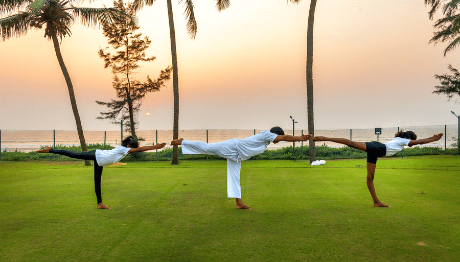 three people doing a yoga asana on the lawn - Caravela Beach Resort Goa