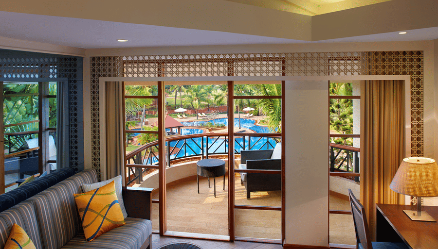 a living Room with sofas, table and access to the balcony - Caravela Beach Resort Goa