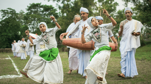 people dressed in native outfits while dancing and playing drums