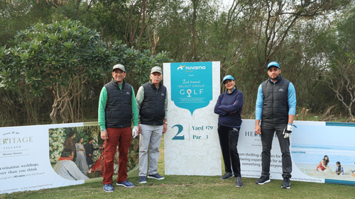 Four people standing together, between them is a flex with a invitation writing on it.- Heritage Village Resorts & Spa