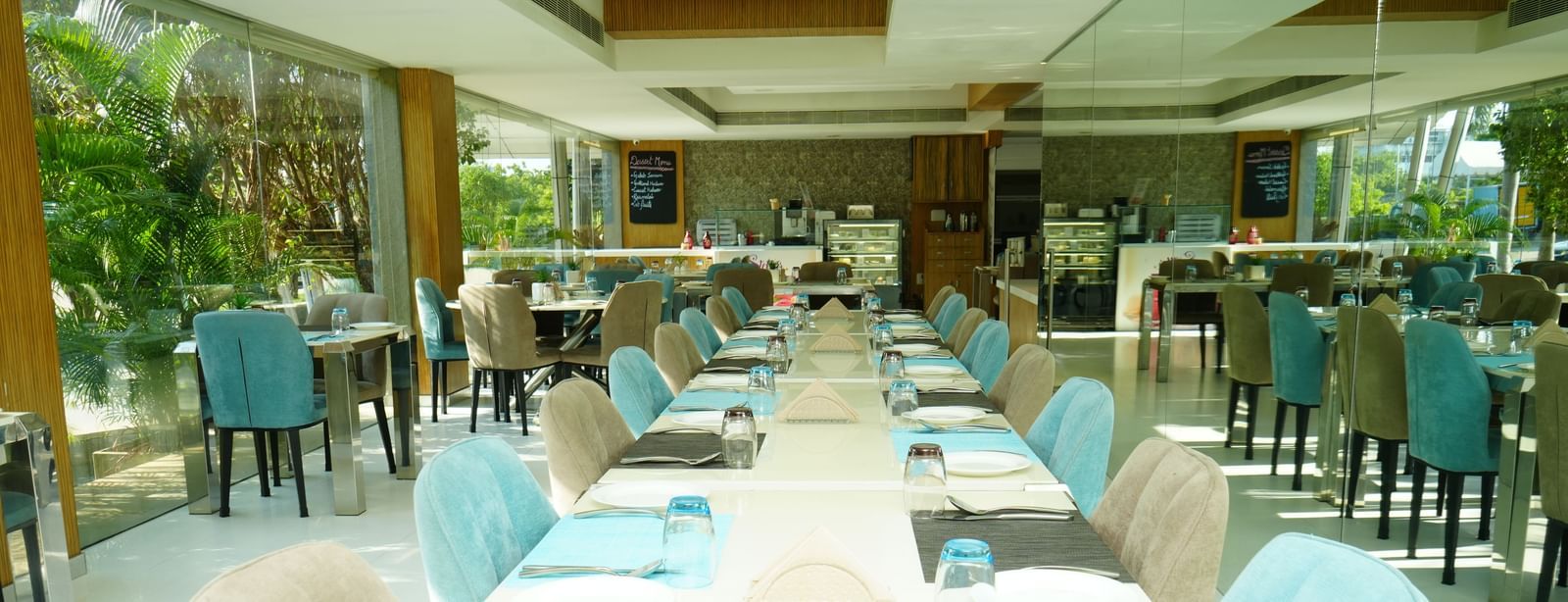 Long dining tables with blue chairs set inside a well-lit restaurant.Long dining tables with blue chairs set inside a well-lit restaurant at  Grande Bay Resort & Spa.