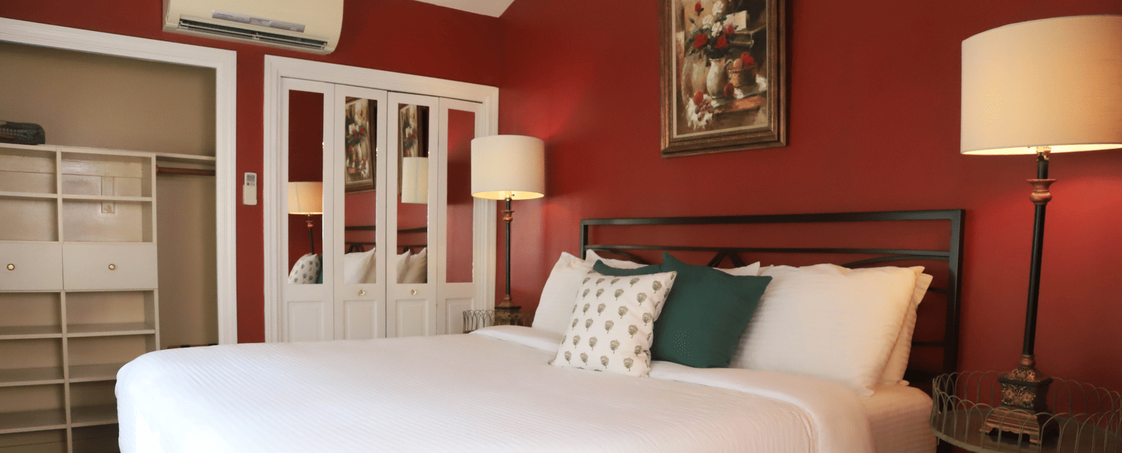 Hotel room with red walls, bed, and a lamp beside the bed at Hartstone Inn.
