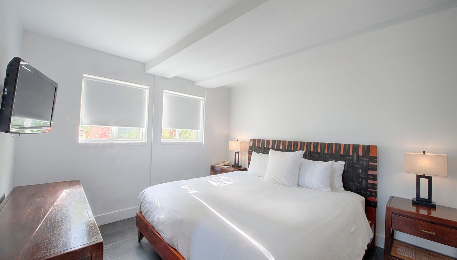 Bedroom at Casa Morada featuring a white bed, wooden furniture, and a wall-mounted TV.