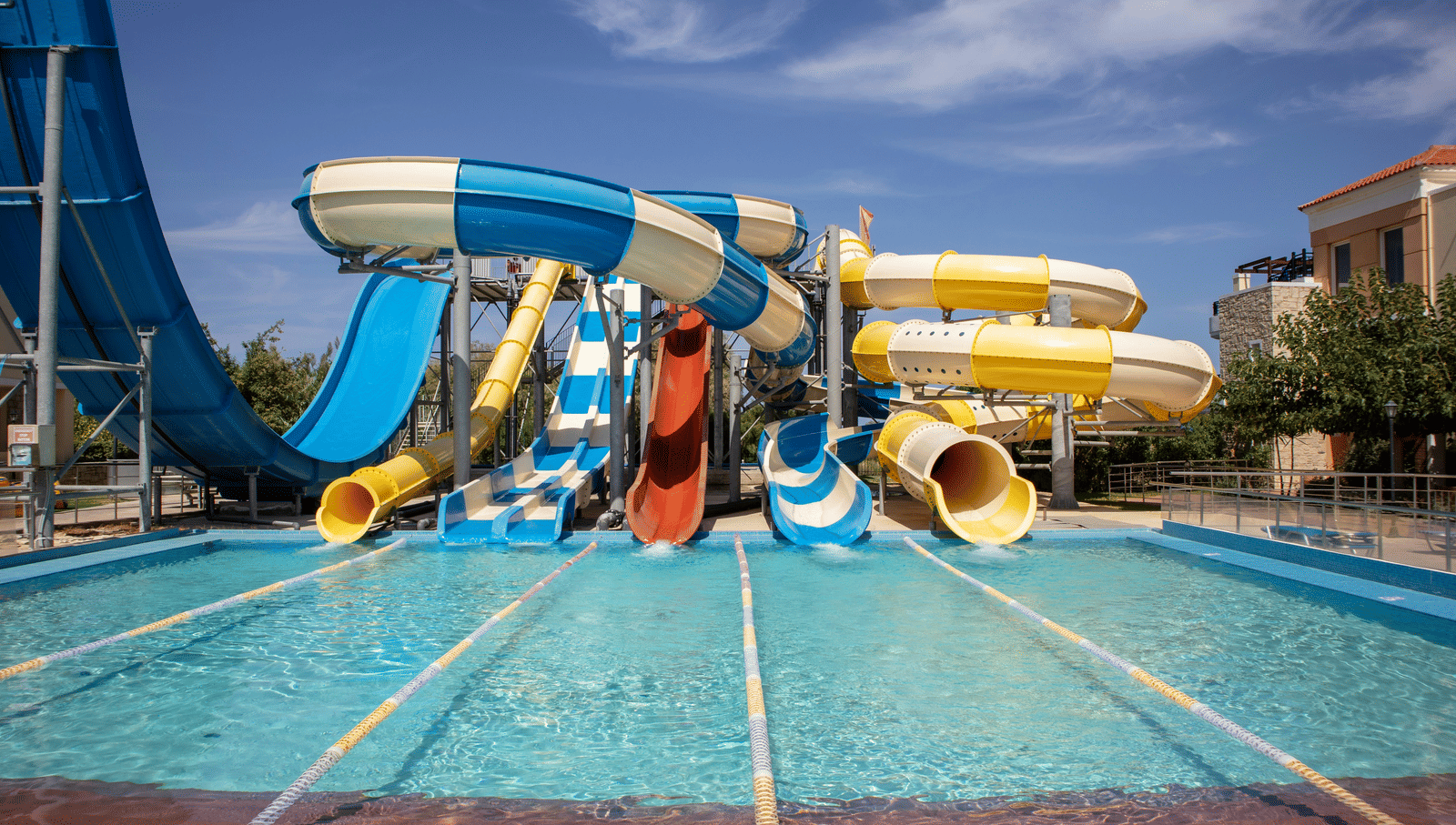 Outdoor water park with slides leading into a large pool under a clear sky.