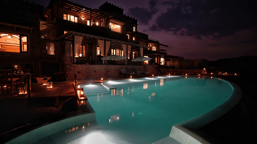 a swimming pool with Chunda Shikar Oudi, udaipur and late evening sky in the background