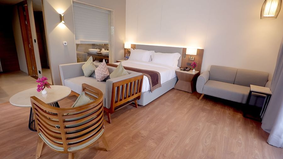Elegant room with a king size bed, grey settee, two stylish chairs, and wooden flooring at Wyndham Garden.
