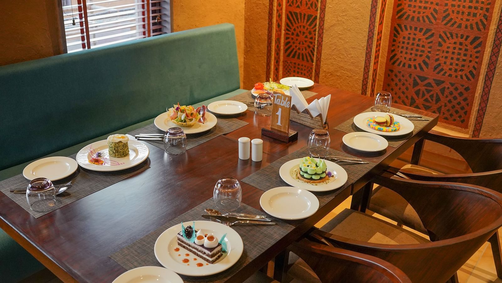 A dining table meticulously set with plates and glasses, ready for guests, at Aamaghati Wildlife Resort.
