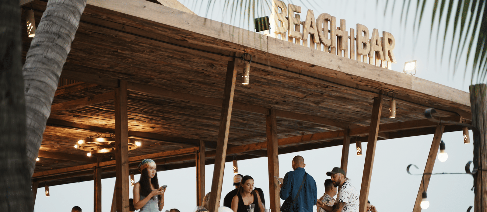 Beach bar at Alibu Resort in Vietnam featuring a wooden structure where people are gathered around.