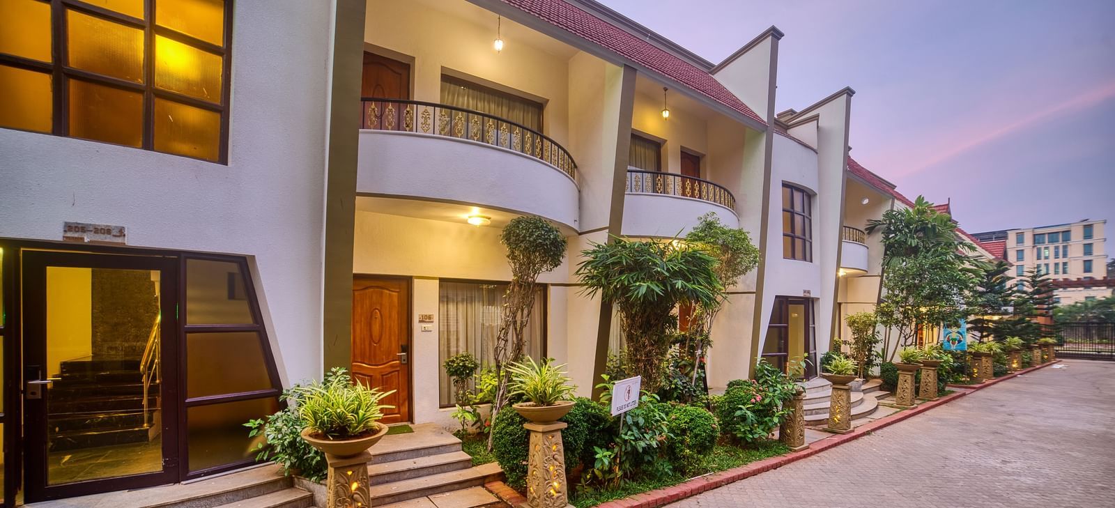 Front exterior view of the Ilara Hotels & Spa, OMR, Chennai with red tiled roofs and green landscaping, showing the main entrance driveway.
