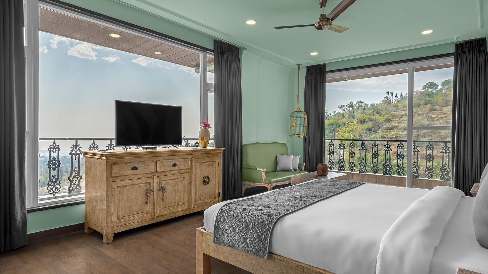 An image featuring a  bedroom with a comfortable bed, and a balcony. wooden flooring, wooden storage units - Atman, dharamshala