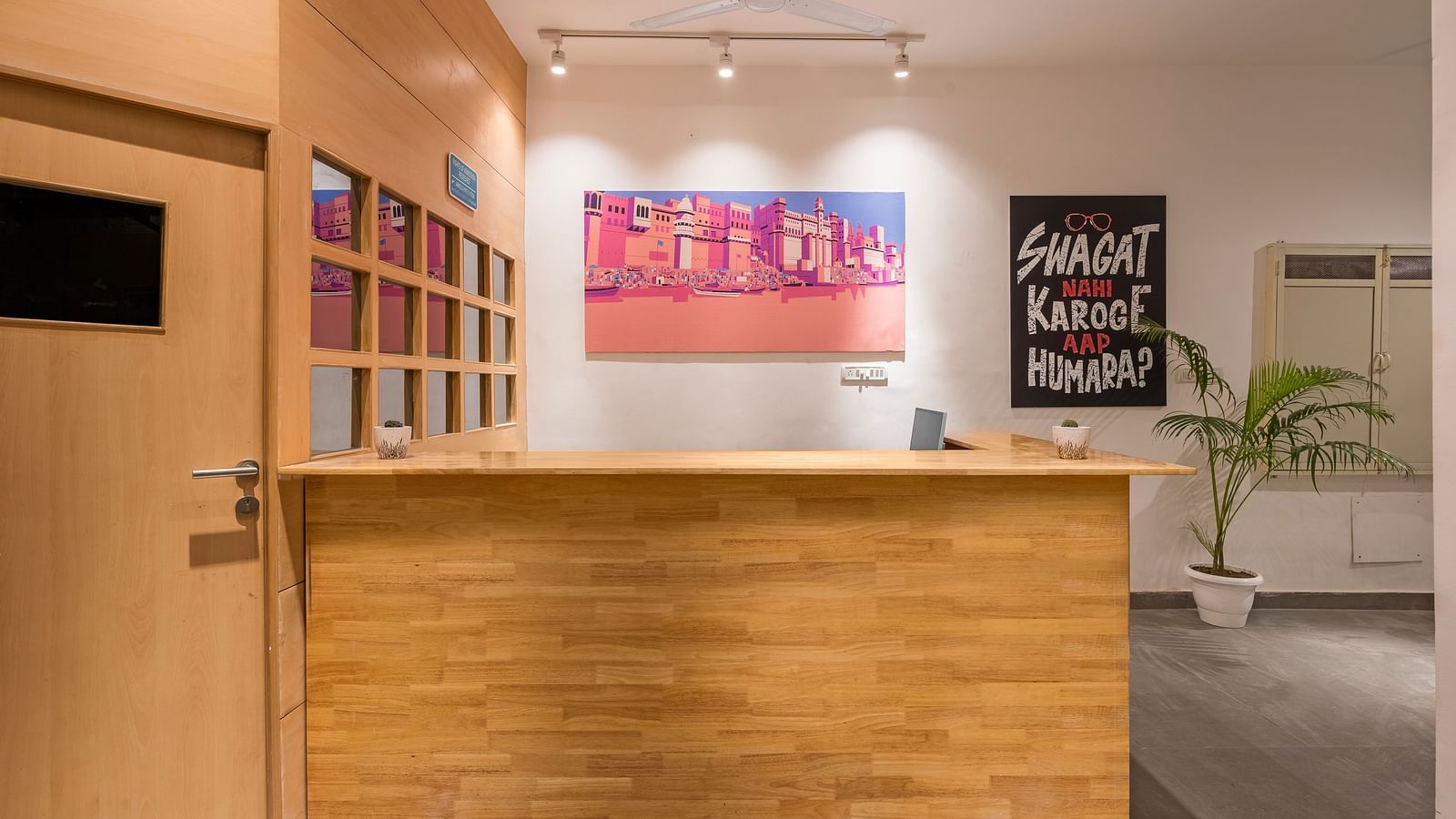 A picture of the reception area at Bedzzz Varanasi, with wooden furnishing and posters on wall.