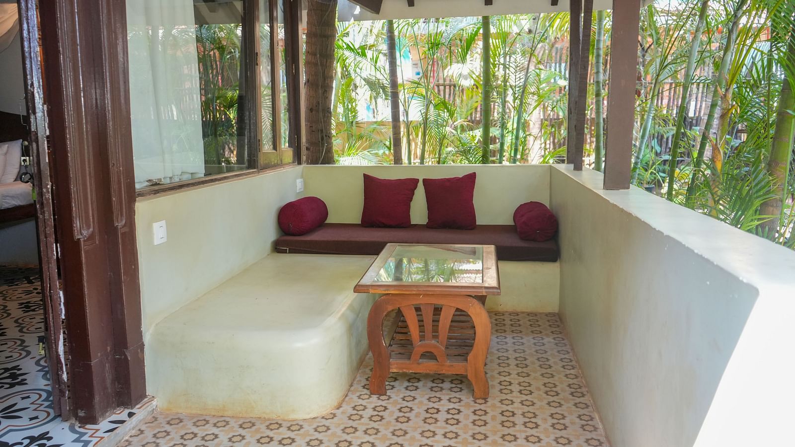 Outdoor-style seating nook with a curved built-in bench and tropical greenery at De Soul Santé, Morjim.