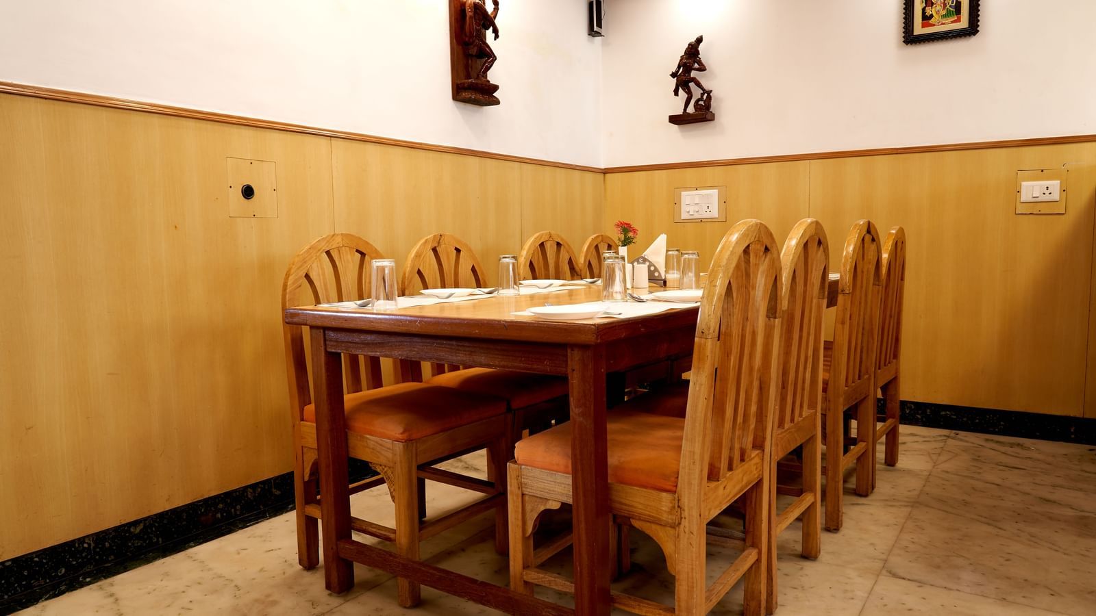 A warm and inviting dining area at Hotel Mamallaa Heritage, furnished with traditional wooden tables and chairs, under soft lighting.