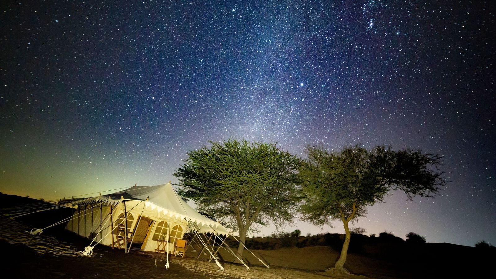 A breathtaking sunset view over the desert, with the campsite situated along the trail, highlighting the vastness of the landscape - MANVAR Resort & Desert Camp