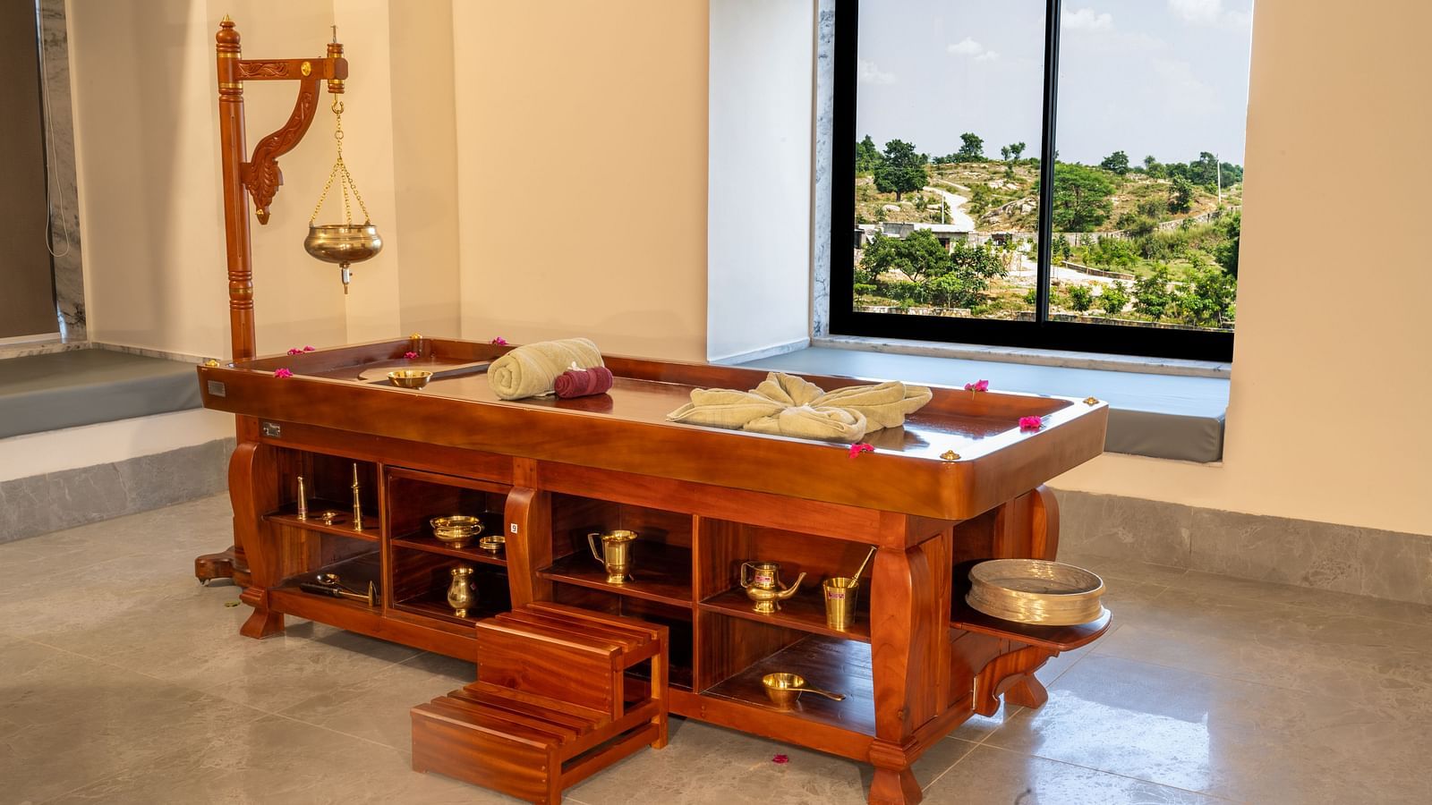 An image of a wooden bed with drawers and cabinets where spa equipment and products are kept - Rajbagh Wellness