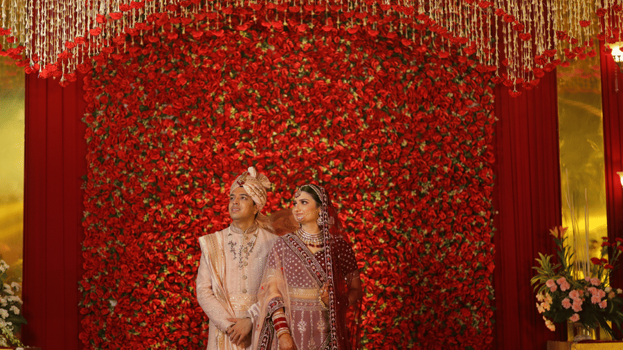 bride and groom posing for pictures with a backdrop of red - heritage village resorts & spa, Manesar