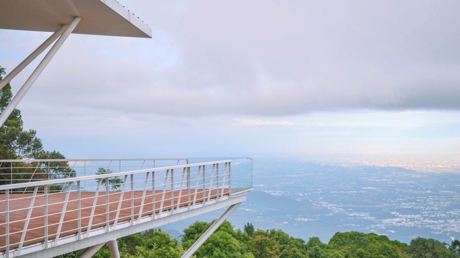 View of a balcony overlooking a lush valley and distant mountains at Ibex Resorts, Coonoor (Tapas).