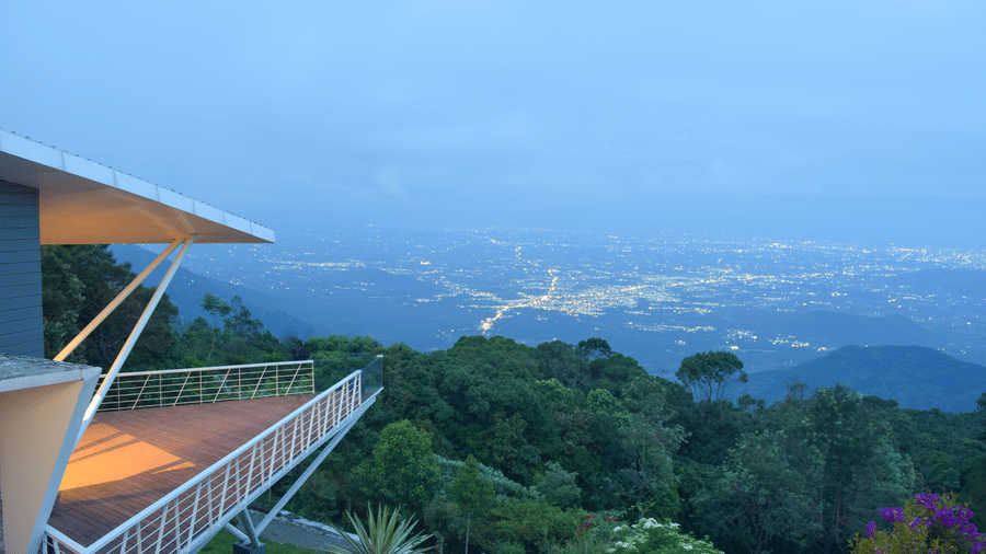 Twilight view of a balcony overlooking a lush valley and distant mountains at Ibex Resorts, Coonoor (Tapas).