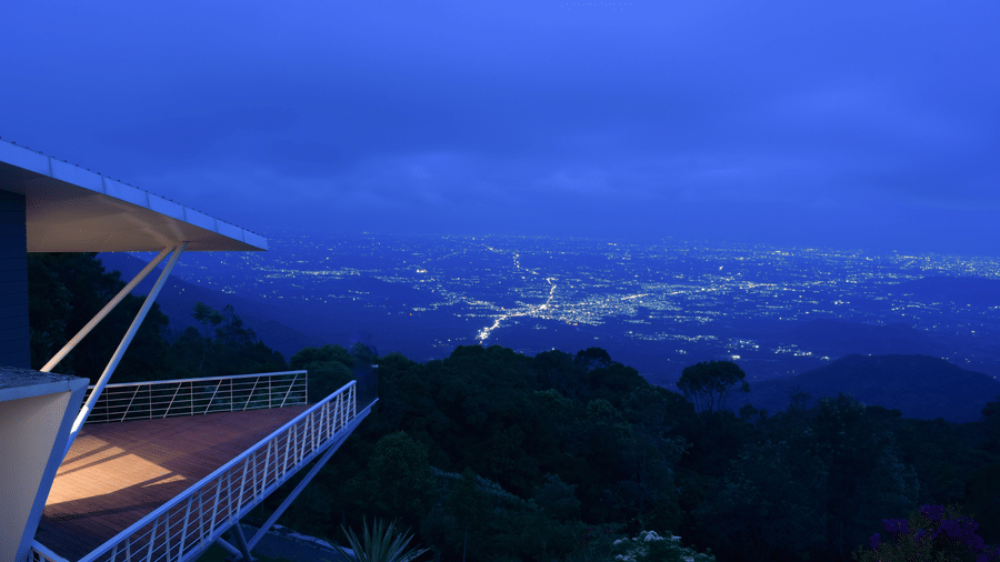 Twilight view of a balcony overlooking a lush valley and distant mountains at Ibex Resorts, Coonoor (Tapas).