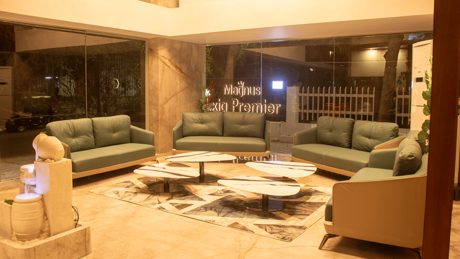 The lobby area with 4 sofas, 4 center table, marble sculpture, and glass entrance at Magnus Lxia Premier, Kalyani Nagar.