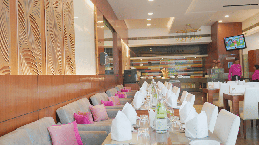 dining area at Nemesia with plush seating, elegant table settings, and a warm and inviting atmosphere. The space features a modern design with wood accents and decorative wall panels.