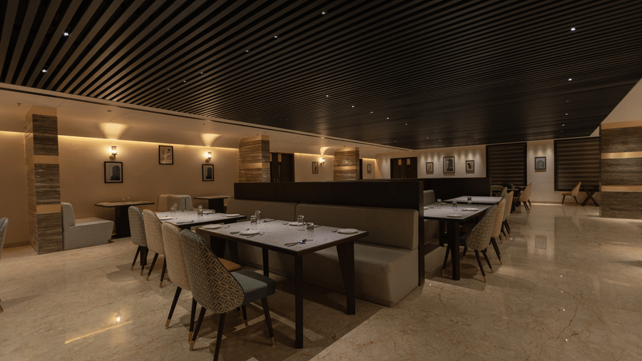 A modern dining space with wooden tables and cushioned chairs at Pride Resort, Jodhpur, under soft ceiling lighting.