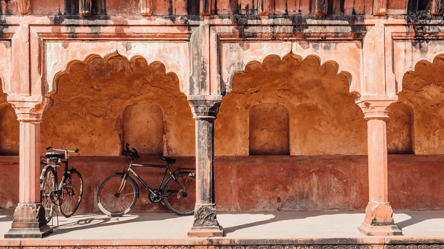 Bicycles are parked inside an Indian building with Islamic style architecture