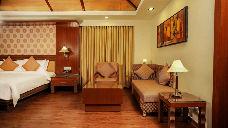 A bedroom with a king bed and a sitting area with wall mounted painting.