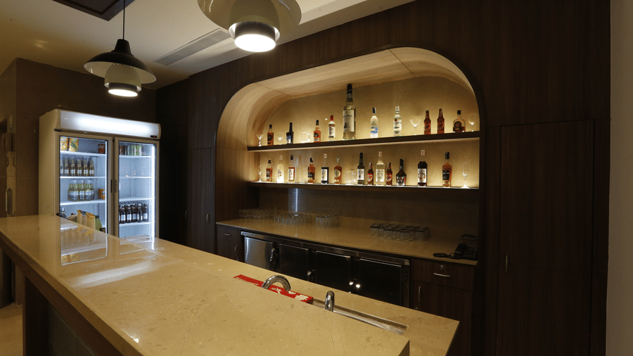 An image of bar counter featuring various liquor bottles placed on shelves and refrigerator - Tulip Inn, Zirakpur