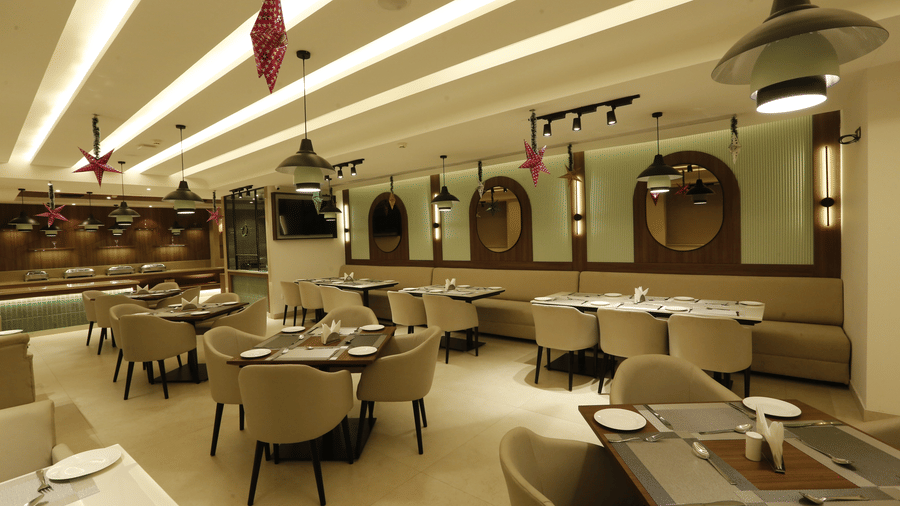 A banner of a restaurant featuring chairs and tables across the room and there are ceiling lights hanging from top - Tulip Inn, Zirakpur