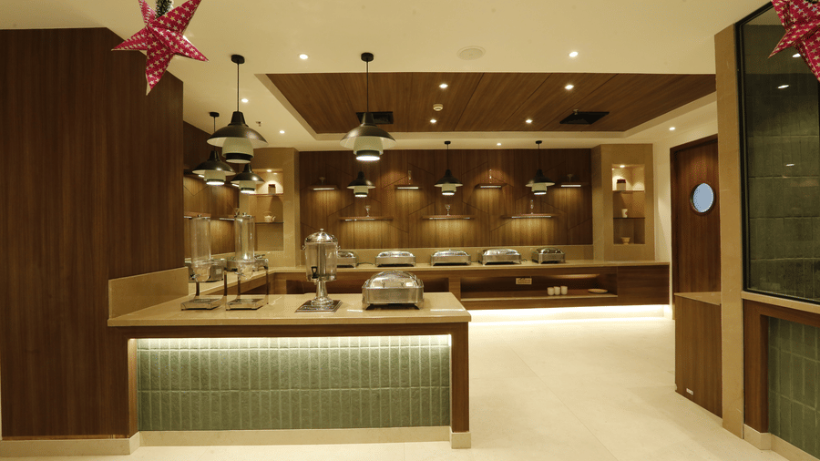 A poster of a buffet hall with several pots kept on the counter top table - Tulip Inn, Zirakpur