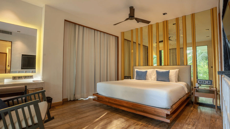 A contemporary bedroom at Azaya Beach Resort Goa featuring a floating wooden bed, timber wall panelling, and soft neutral tones.