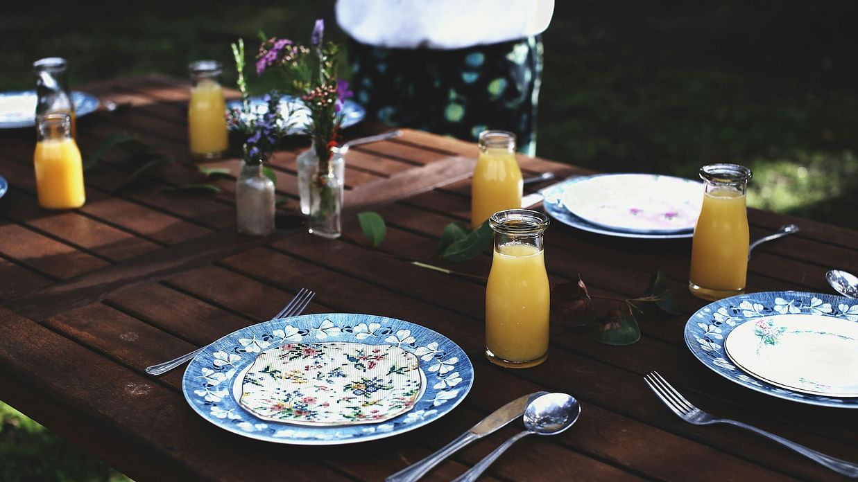 Table setting with elegant dishware composed with juice glasses and vases.