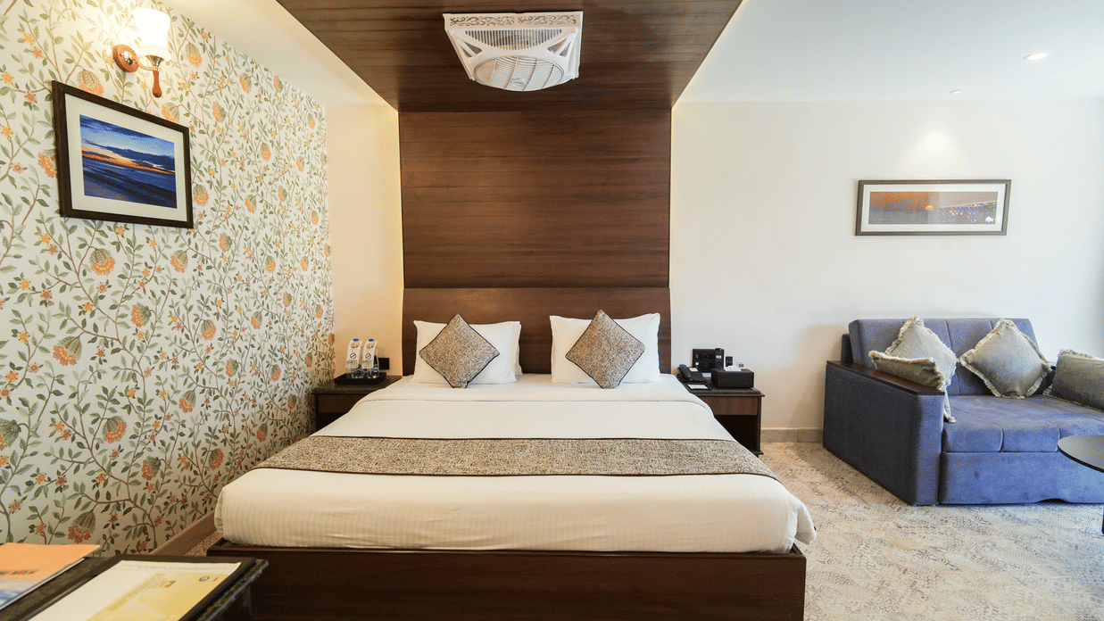 A room at MGM Beach Resorts, with a double bed, spreads, pillows, wall arts, and a sofa.
