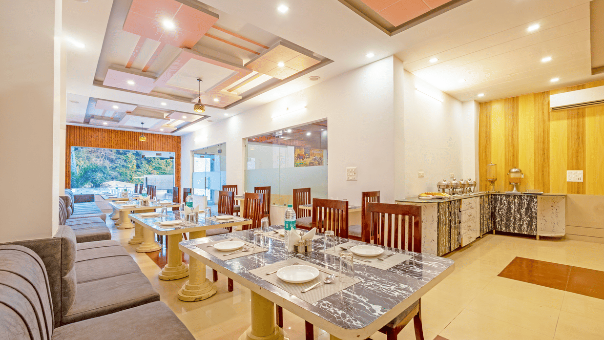 A wide-angle view of a well-lit hotel restaurant interior with modern recessed ceiling lighting - Nature Trails Rishikesh