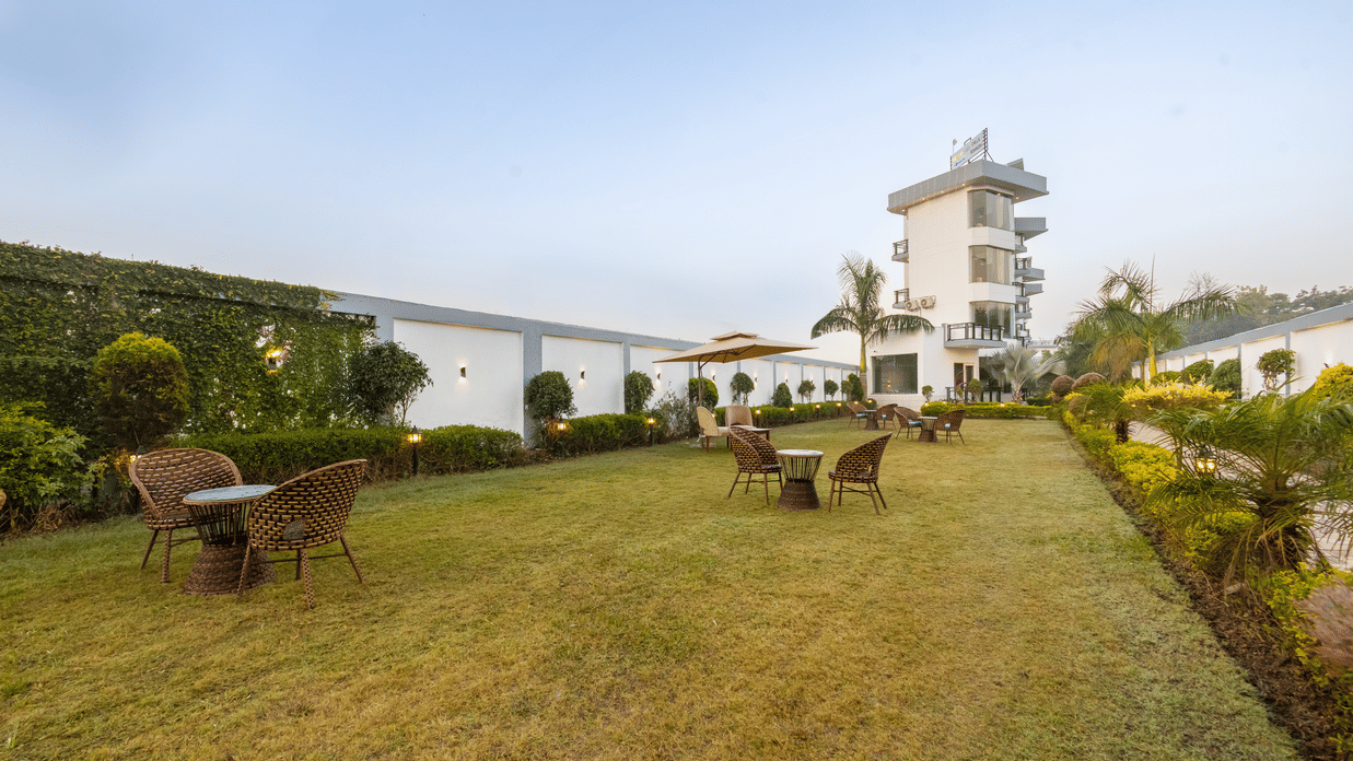 A spacious outdoor lawn at a resort featuring several sets of patio furniture for guests to relax - Nature Trails Rishikesh