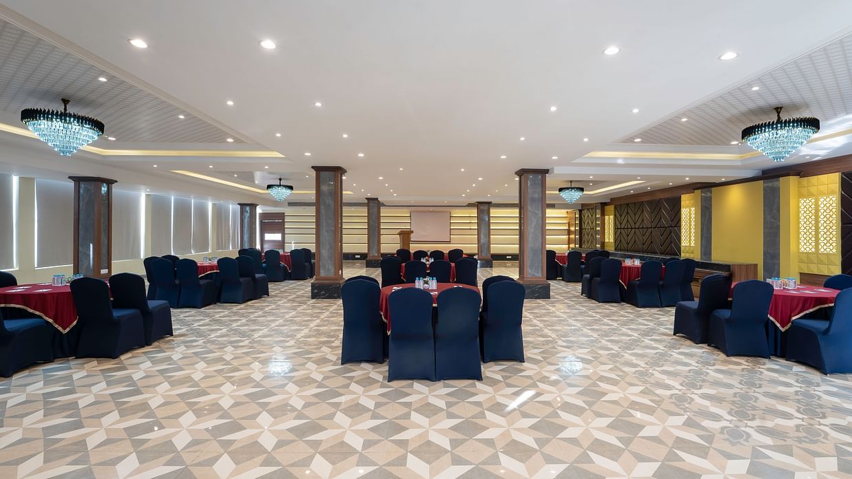 A banquet area is set with tables and chairs, ready for an event -SPT Clarks Inn Suites, Mandi