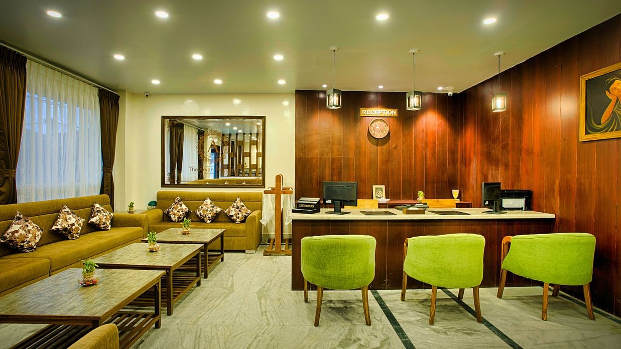 lobby area of a hotel in front of reception area with beautiful green and yellow furniture - the aryan regency
