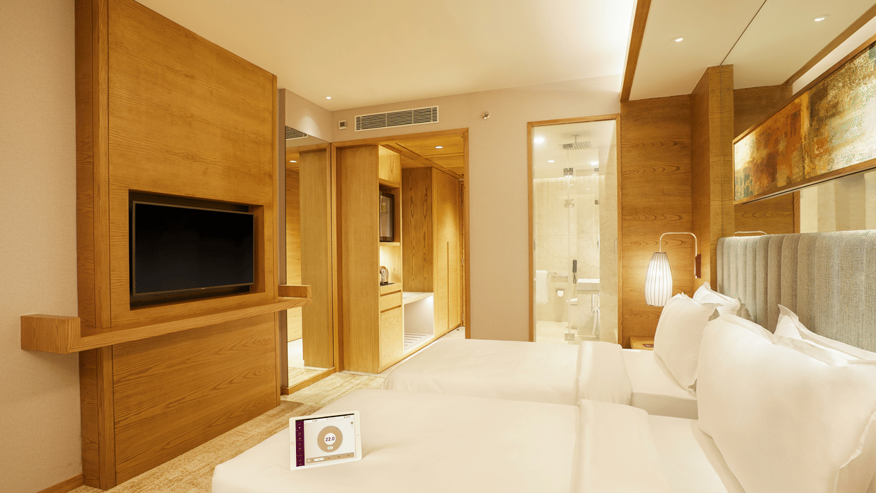 Side view of Premier Rooms featuring a wall-mounted TV and a bedside light in the corner at The Residency Towers Chennai