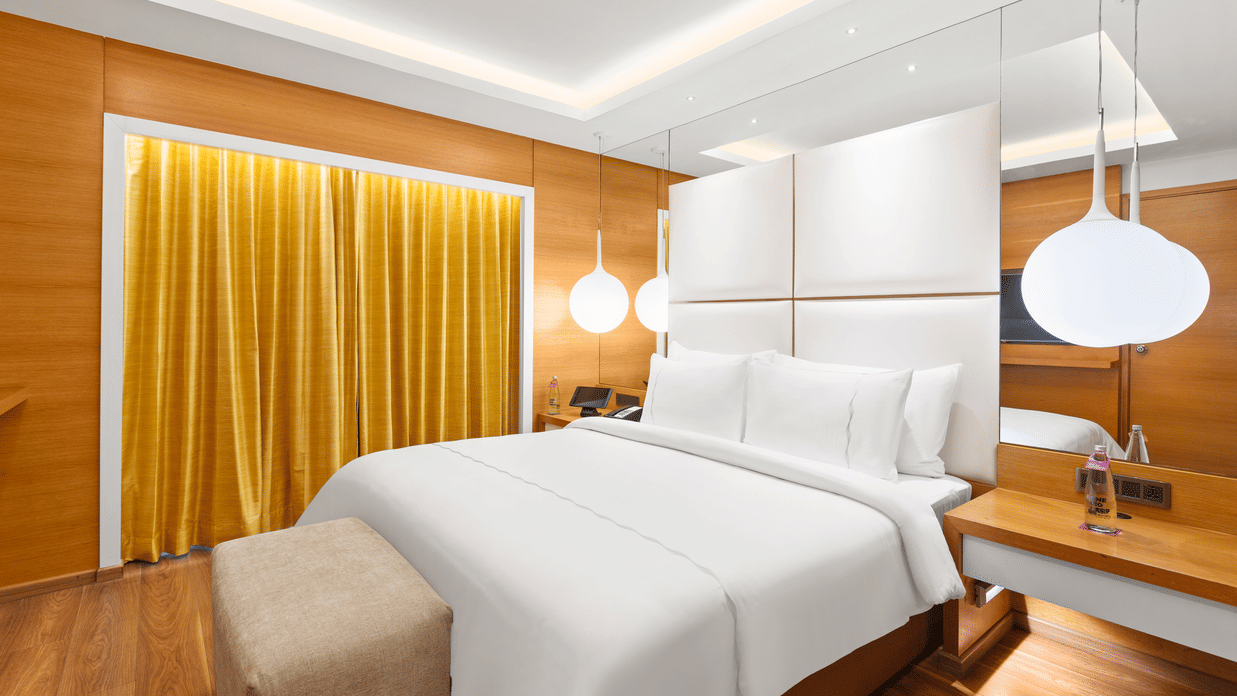 Club Suite room with a cozy high bed and stylish hanging bedside lamps at The Residency Towers Coimbatore