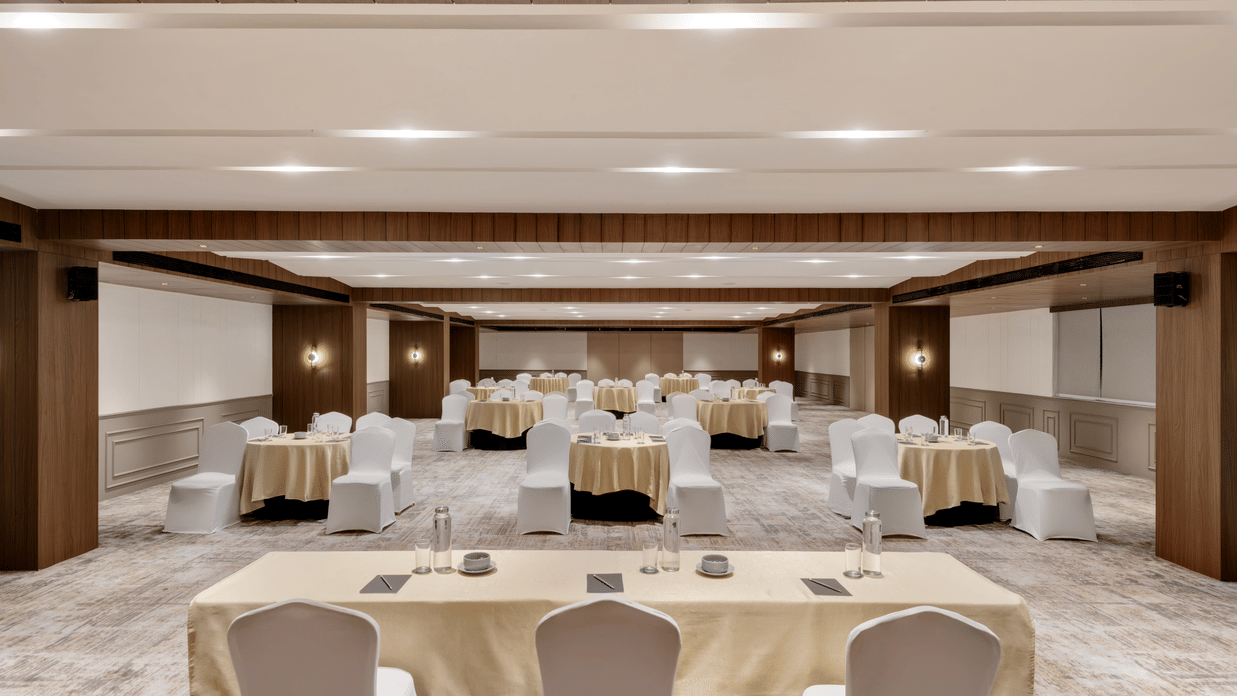 Chairs with round tables arranged at Aura in front of a set of 3 chairs with a rectangular table at Voyage Milestone Hotel And Banquet