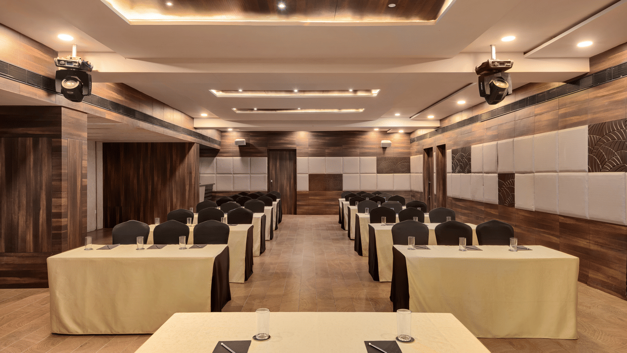 Spectrum hall at Voyage Milestone Hotel And Banquet featuring a table facing chairs and tables arranged in classroom setting in 2 rows