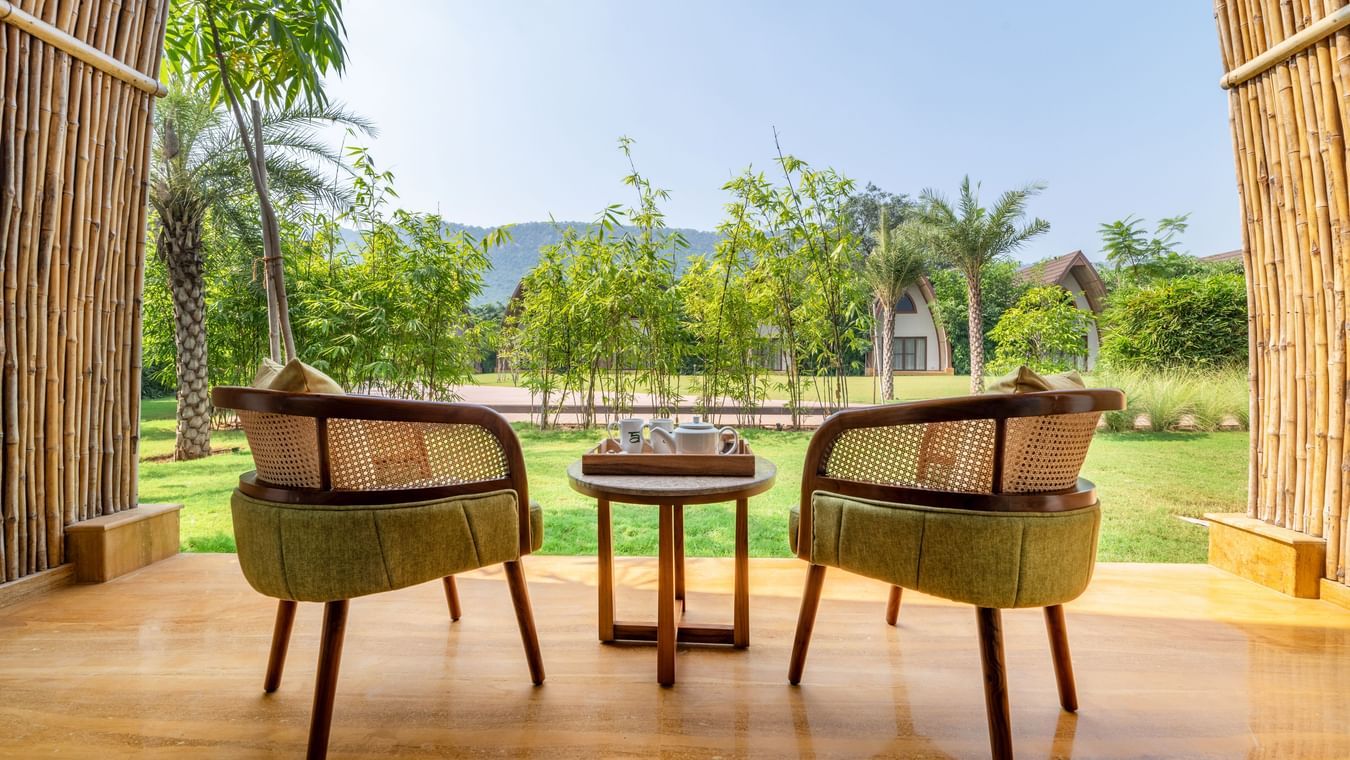 An outdoor seating area for 2, facing an open area with trees and mountains.